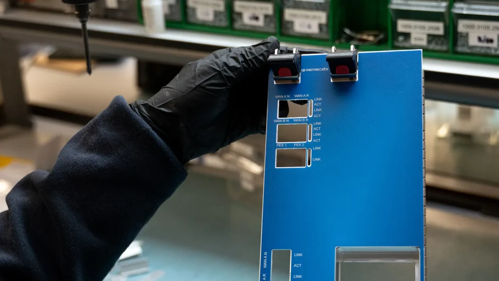blue polycarbonate front panel with adhesive labels for network interfaces and led indicators held by a gloved hand